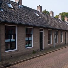 19e eeuws arbeiderswoninkje zonder verdieping onder met blauwe Hollandse pannen gedekt zadeldak, dat doorloopt over de buurpanden