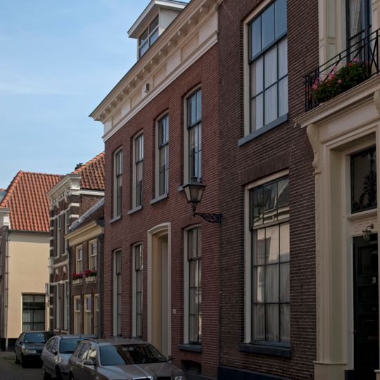 Pand met bakstenen lijstgevel met grote ramen en gepleisterde omlijste voordeur