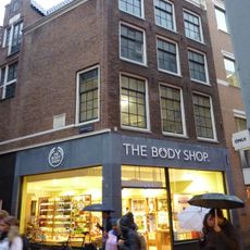 Hoekhuis uit 1561 met voorgevel onder rechte lijst met consoles en hoge gemetselde dakkapel op de zijgevel, waarin gevelsteen