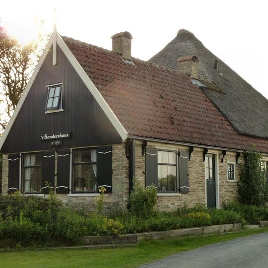 Tegen helling van de 'Hoge berg' stolphoeve met uitgebouwde woonhuis