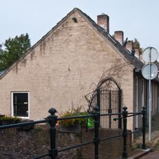 19e eeuws arbeiderswoninkje zonder verdieping onder met blauwe Hollandse pannen gedekt zadeldak, dat doorloopt over de buurpanden