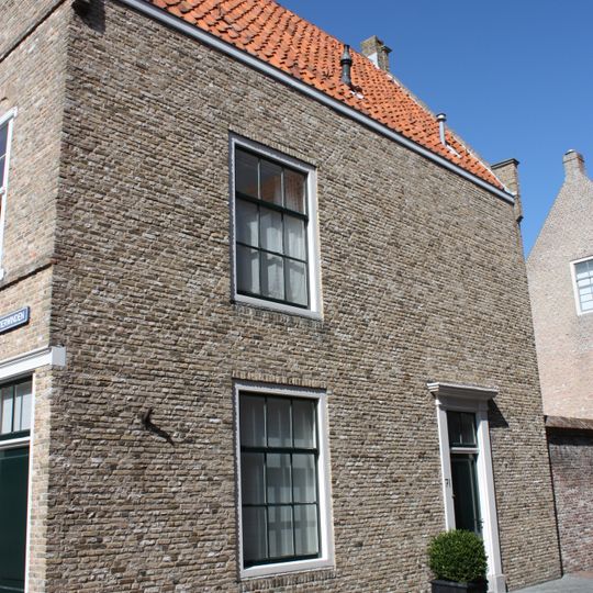 Pand met in schoon metselwerk uitgevoerde trapgevel met topbekroning, de treden afgedekt met natuurstenen platen