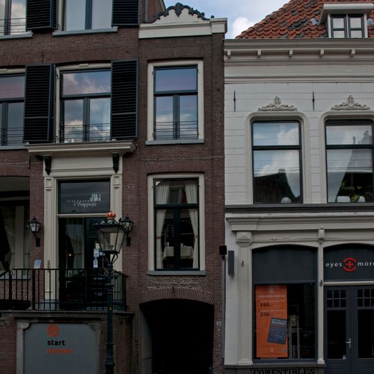 Overbouwde gang met zijlisenen en lijst waarop een houten gesneden bekroning