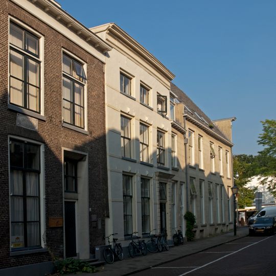 Pand met voordeur in pilasteromlijsting in gepleisterde gevel met rechte kroonlijst