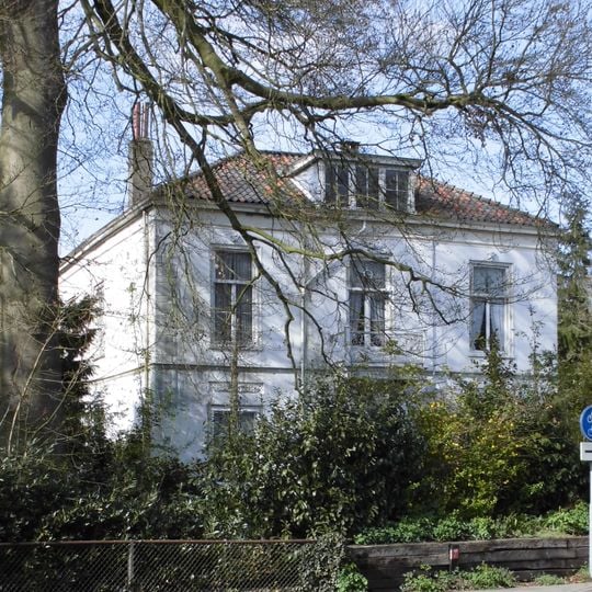 Vierkante gepleisterde villa, de tamelijke strenge, spaarzaam in eclectische trant versierde gevels voorzien van middenrisalieten