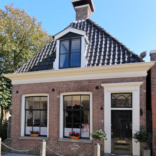 Pand onder voor afgeschuind zadeldak met topschoorsteen met bord en dakkapel