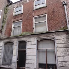 Huis met schilddak, en lijstgevel, beganegronds gebosseerd blauwgepleisterd, daarboven schoon werk, ramen met kleine roedenverdeling