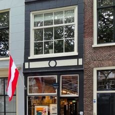 Pand met gepleisterd lijstgeveltje ter breedte van een vensteras. Schuiframen in de verdieping