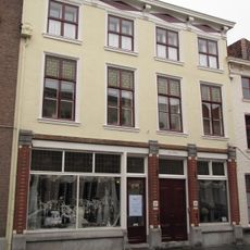 Huis met witgepleisterde lijstgevel en kroonlijst op voluutvormige consoles