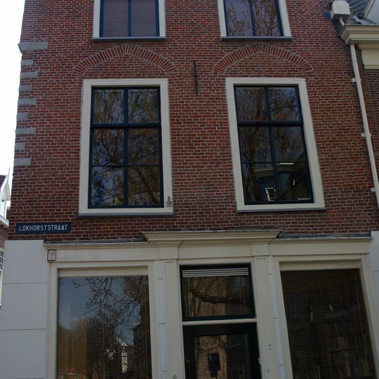 Hoekpand met ontlastingsbogen boven de vensters in de verdieping. Pui uit de tweede helft 19e eeuw, houten kroonlijst