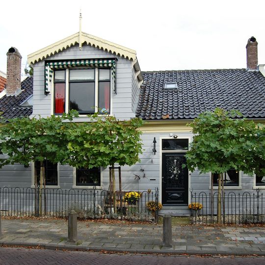 Houten huis onder zadeldak voorzien van grote dakkapel met gesneden lijst