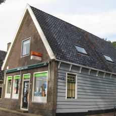 Gebouw met moderne stenen voorgevel, overigens oorspronkelijk met hoge kap