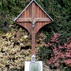 Überdachtes Holzkreuz mit Torso auf Blausteinsockel