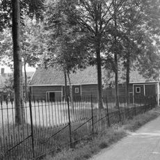 Kleine hoeve. Gepleisterd woonhuis met pannen gedekt. Voordeur in langsgevel aan de straat met bewerkt kalf. Dicht bijeen gelegen staafankers. Bakgoot op klossen. T-schuiframen met paneelluiken.