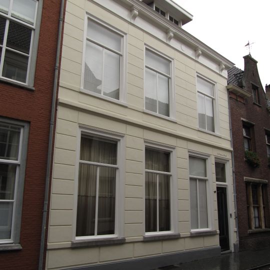Huis met gebosseerd witgepleisterde lijstgevel