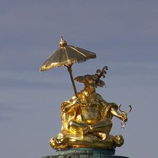 Figur eines Mandarin mit aufgespanntem Schirm und Caduceus.