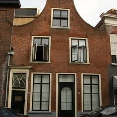 Huis met gaaf bewaarde tuitgevel met deur, voorzien van klopper en neo-gotisch bovenlicht