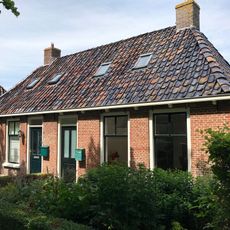 Breed landelijk pand met goot op klossen onder schilddak met twee hoekschoorstenen (vormt een geheel met nr. 29)