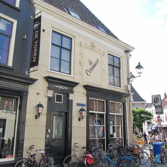 Huis met schilddak en gepleisterde lijstgevels en versierde ingangspartij aan beide zijden, met Korinthische pilasters en guirlandes in het hoofdgestel