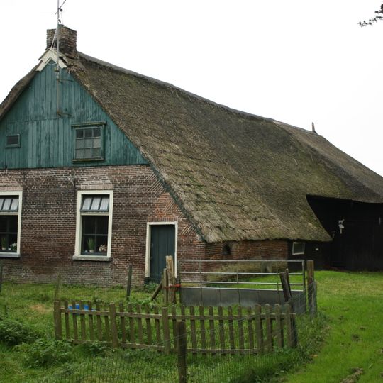Boerderij met zijbaander onder rieten wolfsdak met toef