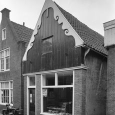 Huis met houten van uitgeschulpte windveren voorziene topgevel