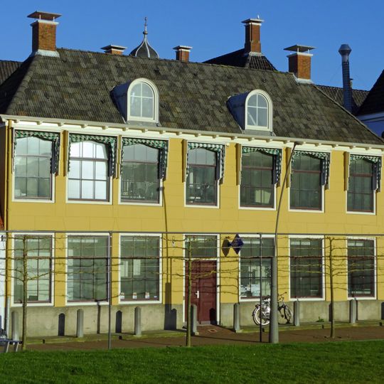 Zeven traveeën breed pand met gepleisterde gevel, rechte kroonlijst en halfronde dakkapellen