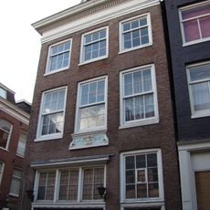 Huis met voorgevel onder rechte lijst waarop een rondbogige dakkapel