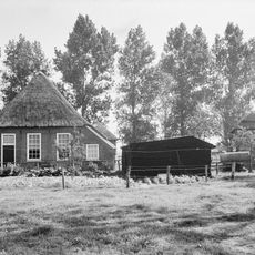 Boerderij onder rieten schilddak met onderschoer. In de voorgevel vensters met roedenverdeling en natuurstenen onderdorpels.