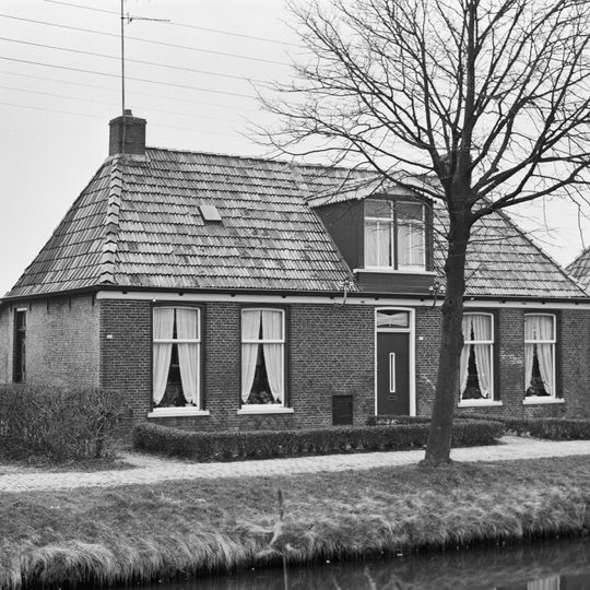 Landelijk pand met goot op klossen onder schilddak met hoekschoorstenen