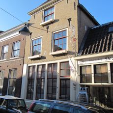 Pand met afgeknotte trapgevel. Het huis draagt een schilddak, dat achter aansluit tegen een puntgevel. In de voorgevel ontlastingsbogen en drie sierankers. Onderpui omstreeks 1800