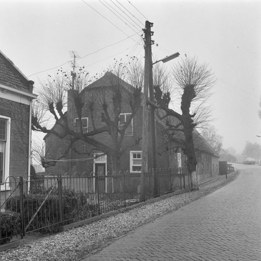Boerderij, evenwijdig aan de weg gebouwd, onder rieten wolfdak. In de voorgevel vlechtingen, vensters met kruiskozijnen en luiken