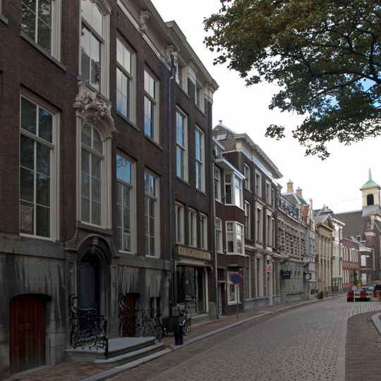 Pand met eenvoudige lijstgevel met zijpilasters, rijk geprofileerde kroonlijst en in de mezzanino vensters, die in de kroonlijst doorlopen
