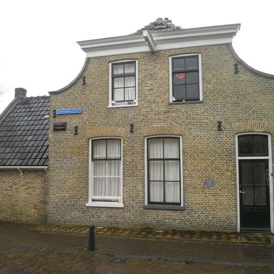 Hoekpand aan de haven met ingezwenkte afgeknotte gevel aan de Commandeurstraatzijde en aan de havenzijde erker en zijtuin