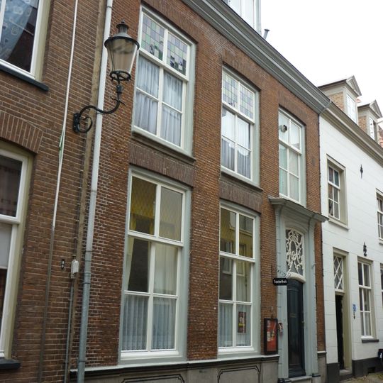 Woonhuis en opslagruimte. Gevel uitgevoerd in baksteen. Deur met houten pilasters en rijk versierd bovenlicht