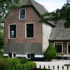 Boerderij met langgerekt zomerhuis. Dwars woonhuis met opkamer, waarvan de puntgevel ontlastingsbogen van de oorspronkelijke vensters heeft