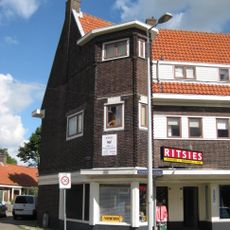 Blok met winkels met brede luifel en daarboven woningen, bouwstijl Amsterdamse School, onderdeel van het centrale achthoekige plein van Tuindorp Nieuwendam