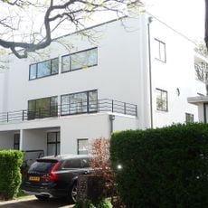 Vrijstaand, in baksteen opgetrokken, witgepleisterd, rechtafgesloten, vlakgedekt blok van twee woonhuizen