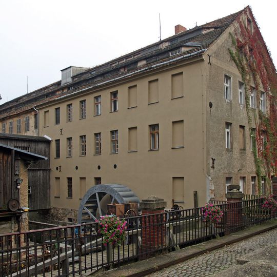Kunstmühle; Zwei Mühlengebäude mit Verbindungsgang, Nebengebäude, Mühlgraben, Wehr, und Zufahrtsbrücke, im unmittelbar an der Straße gelegenen Hauptbau der überwiegende Teil der 1930 installierten Technik noch erhalten Neißetalstraße 33