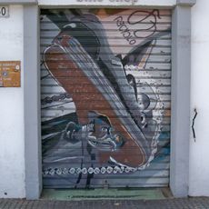 Mural que representa en primer plano la biela, los platos y el pedal de una bicicleta en el momento en el que el ciclista da una pedalada. El ciclista muestra un tatuaje de Recyclo Bike en la pierna.