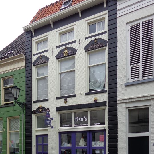 Pand met gevel met jongere gootlijst en werkplaatsingang