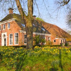 Grote boerderij met woonhuis met omlijste ingang en grote aan de voorzijde afgewolfde kap