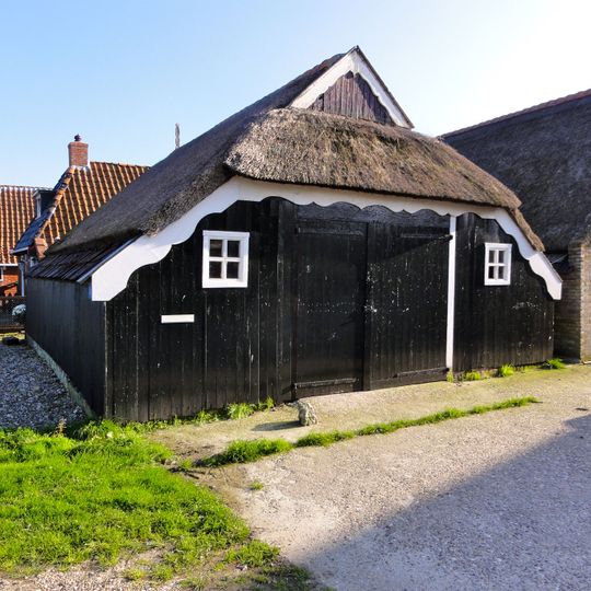 Houten schuur op bakstenen fundering onder rieten wolfsdak met uileborden
