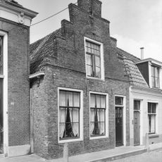 Pand onder zadeldak tegen trapgevel met overhoekse toppilaster