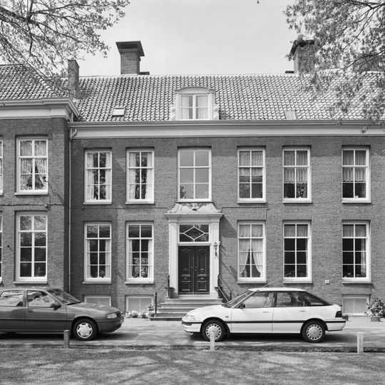 Huis met sobere lijstgevel en stoep, hardstenen versiering boven de deur, tegenhanger van nr 18