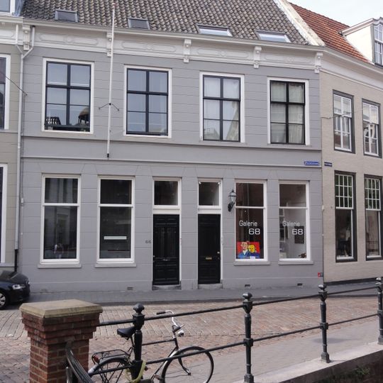 Huis met gebosseerd gepleisterde gevel met kroonlijst op consoles