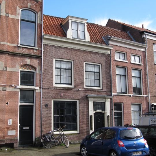 Pand met rechte kroonlijst, houten ingangsomlijsting met zijlichten en gebeeldhouwde deur