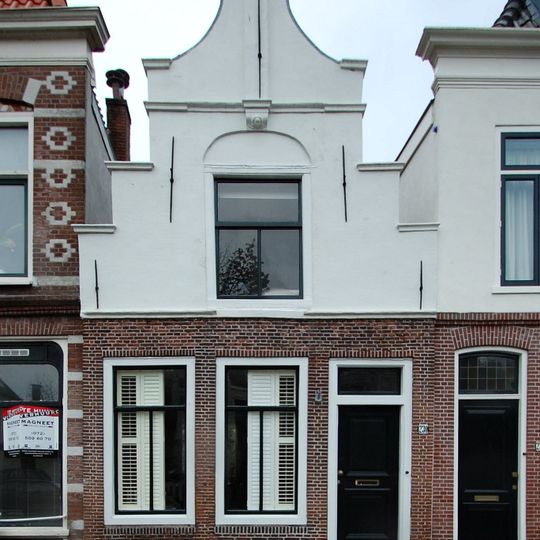 Pand met trapgevel, de ingezwenkte gepleisterde top bekroond door pilaster op gebeeldhouwd kraagsteentje