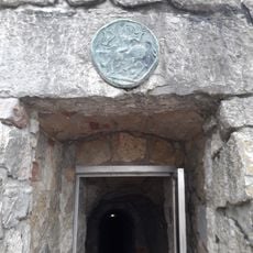 Bronzový reliéf nad východem z Koněpruských jeskyní