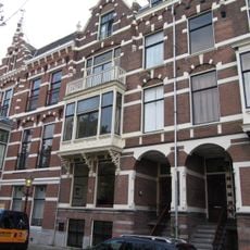 Pand in neo-renaissance trant met links topgevel. Brede houten erker op korbelen. Gevelversiering met banden en blokken. Rechts getoogde ingangspartij