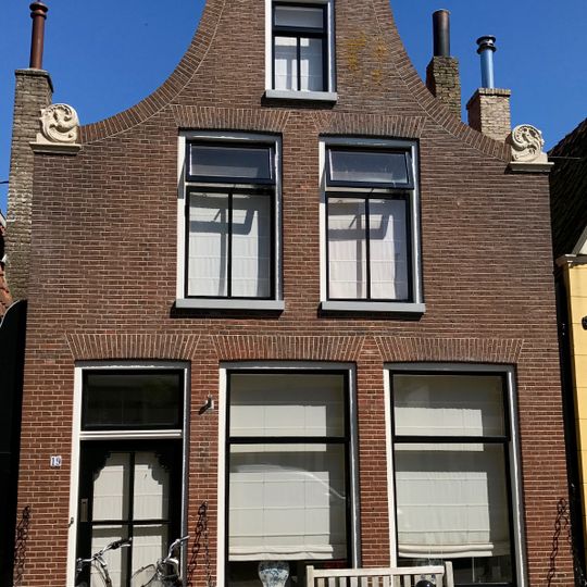 Pand onder zadeldak met eenvoudige klokgevel met aanzetkrullen en gezwenkte bekroning